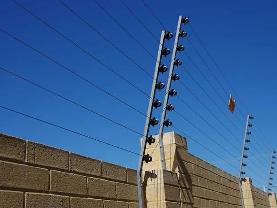 Multi-strand electric fence on brackets above a brick boundary wall